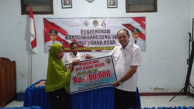 Kepala Desa Geger Kecamatan Geger Kab. Madiun, Samsudin saat menyerahkan BLT-DD kepada salah satu penerima manfaat.